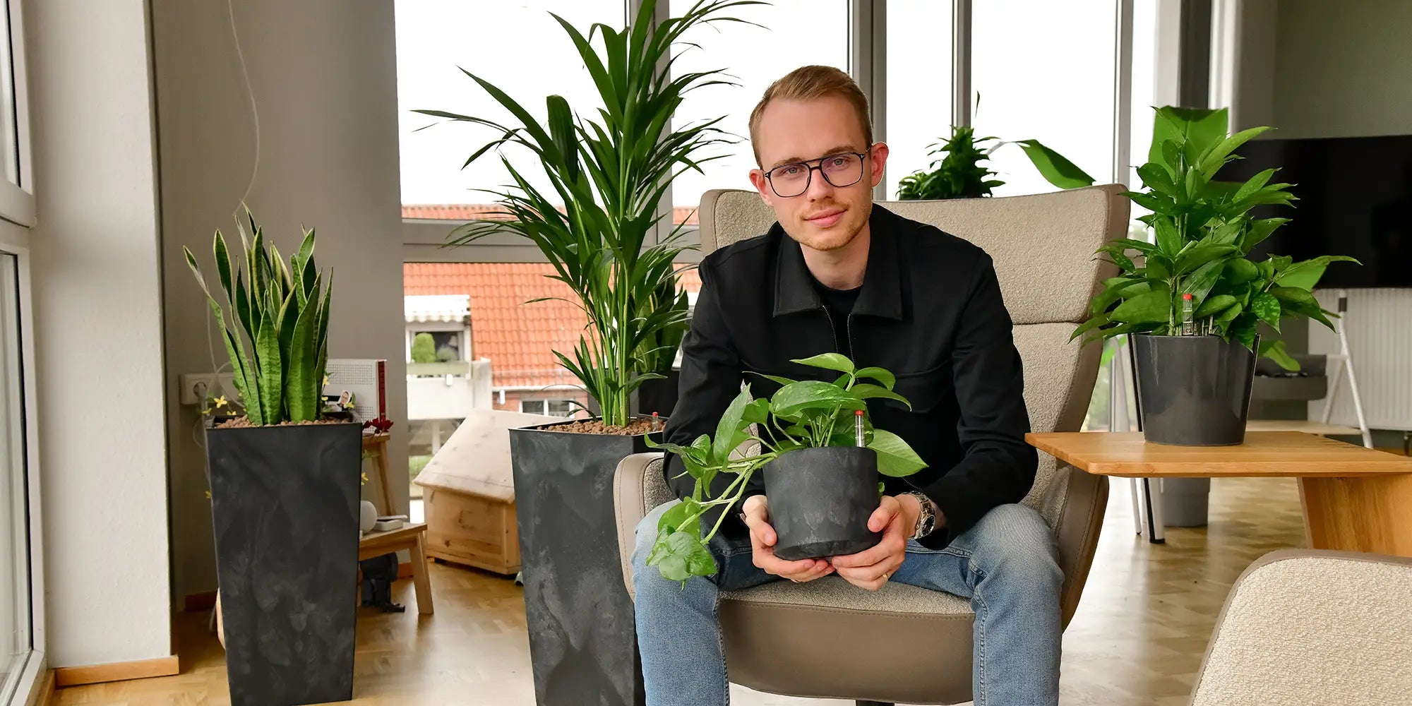 Glücklicher Mann mit Pflanzen in seinem Büro