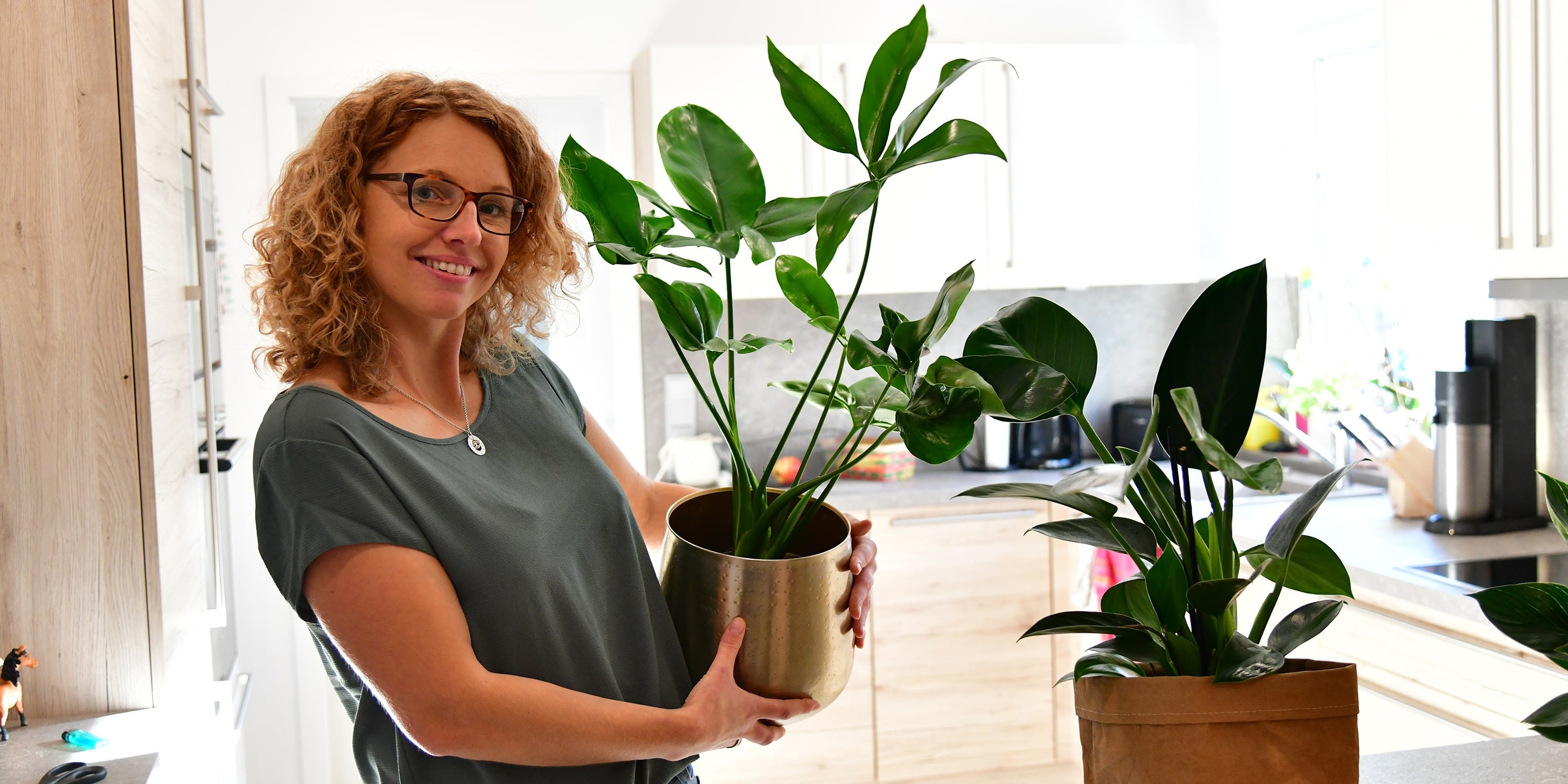Strahlende Frau mit Pflanze in Arm