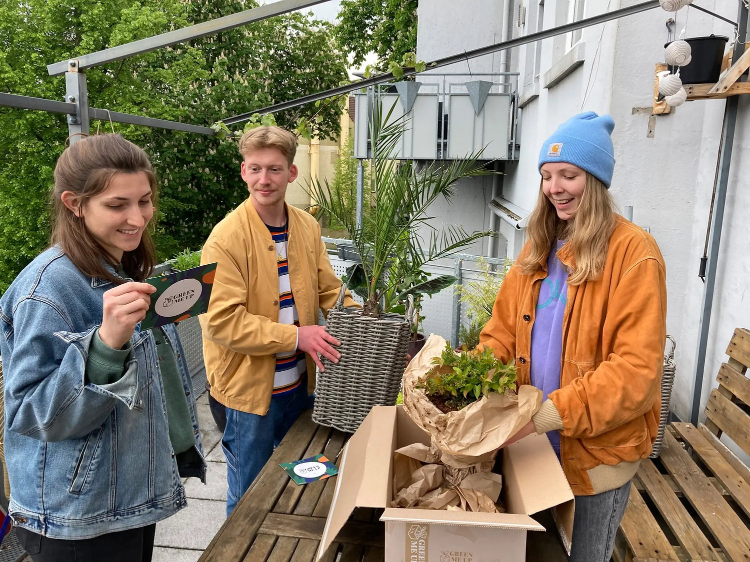 2 Frauen und ein Mann öffnen Green Me Up Pakete