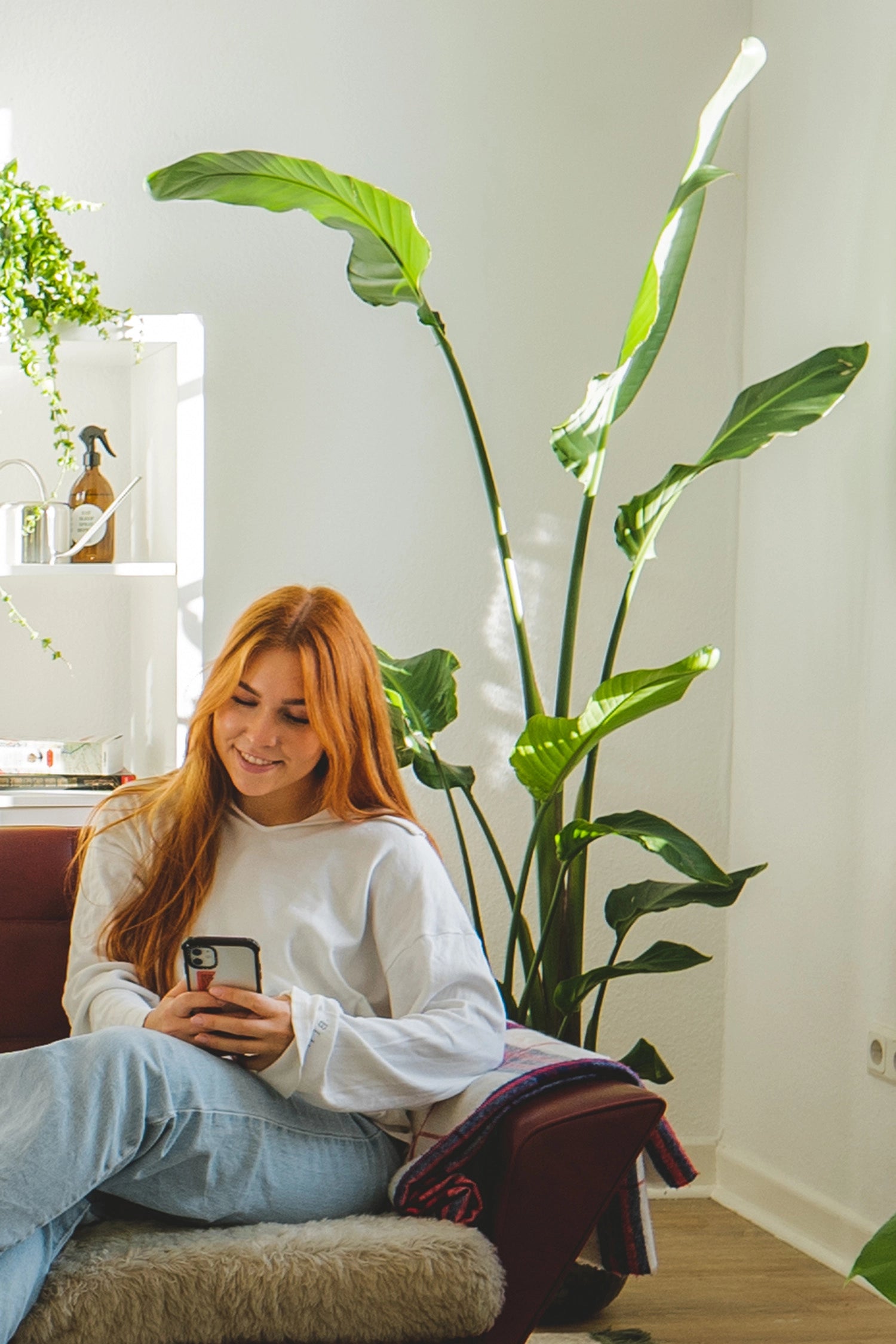 Frau mit Strelitzie im Hintergrund auf der Couch